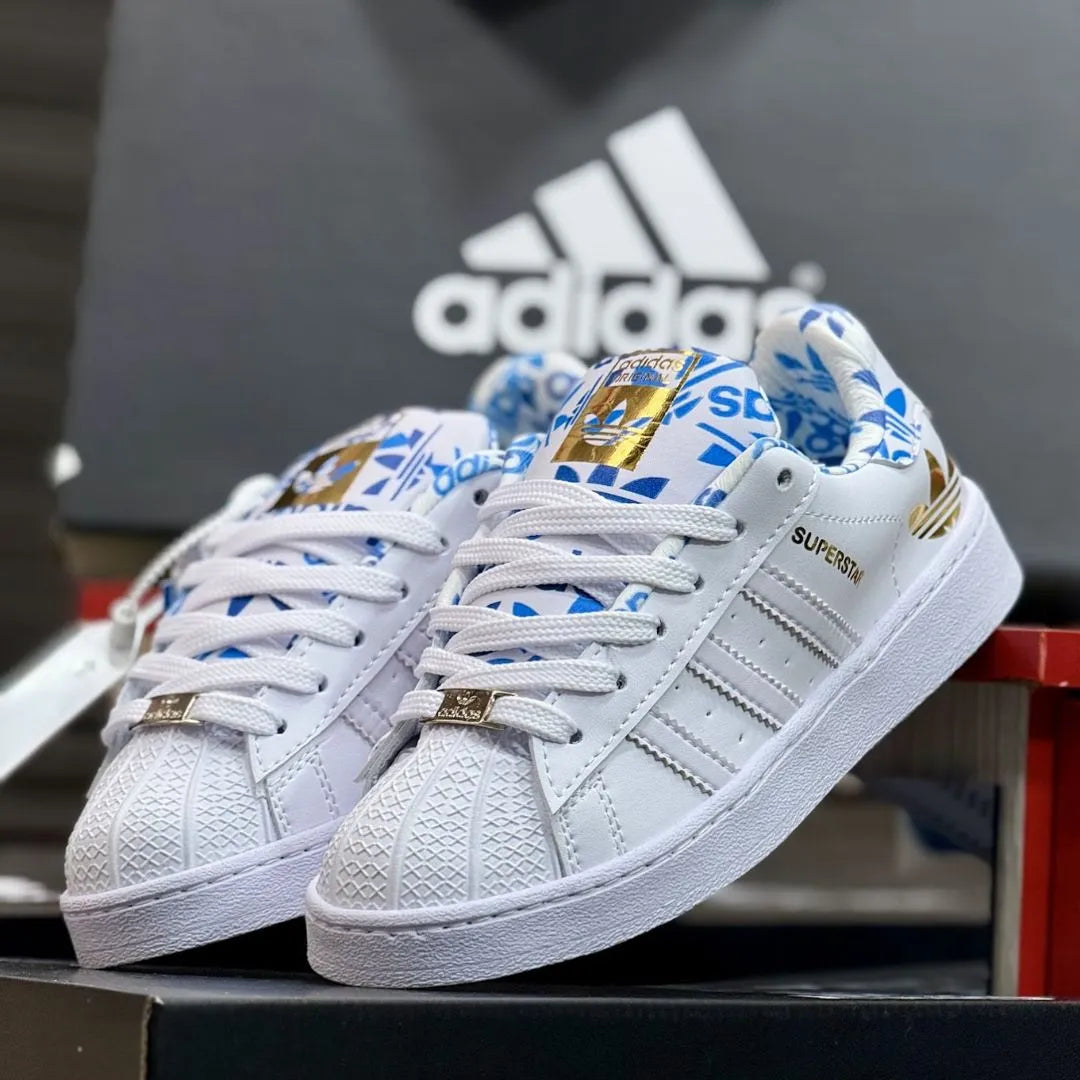 Zapatilla Adidas Unisex Superstar Blanco Azul y Dorado